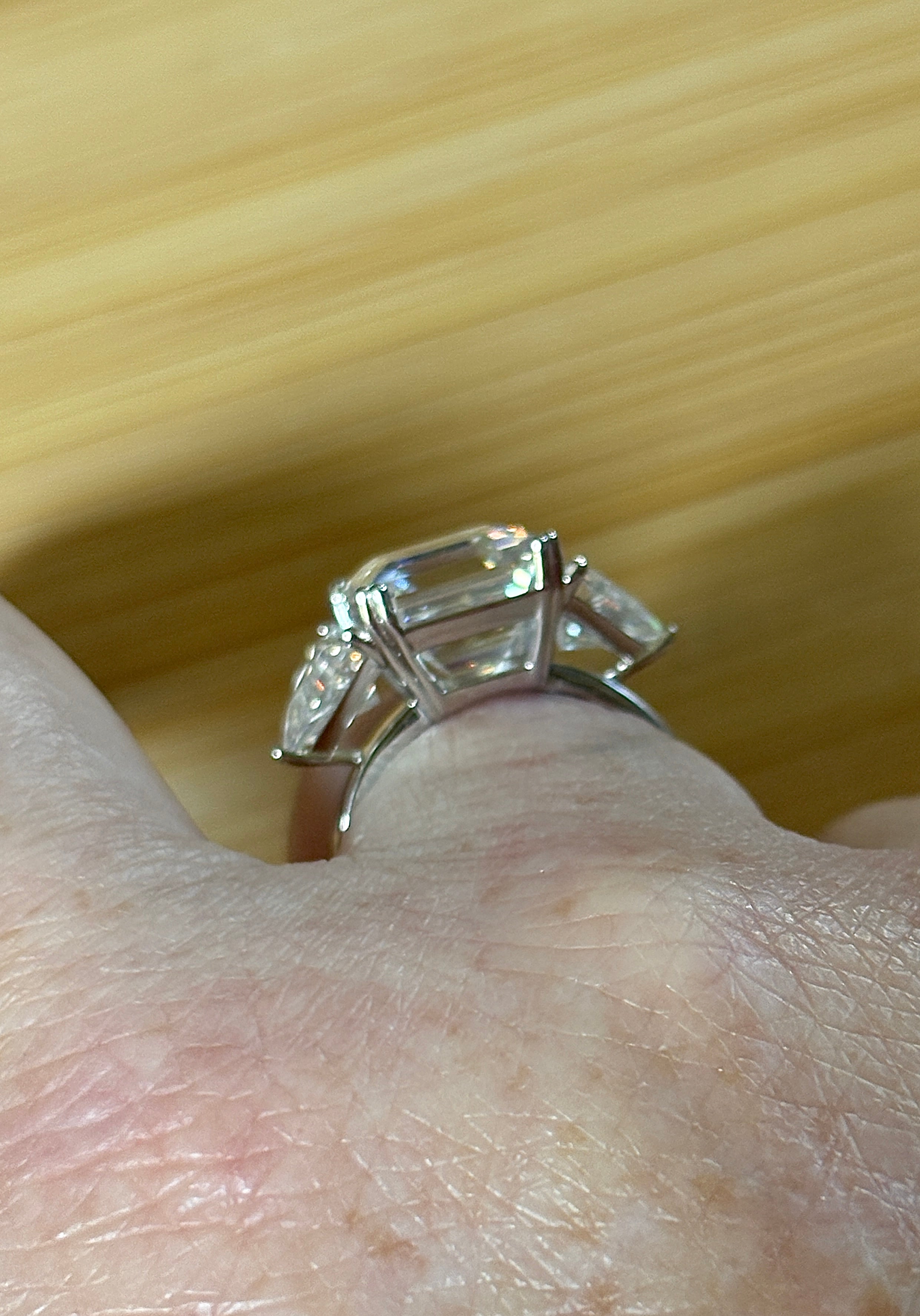 A 9.4cttw Moissanite statement ring with a 7ct Asscher-cut center stone and (2) 1.20ct Moissanite trillions, with bright 14k white rhodium!