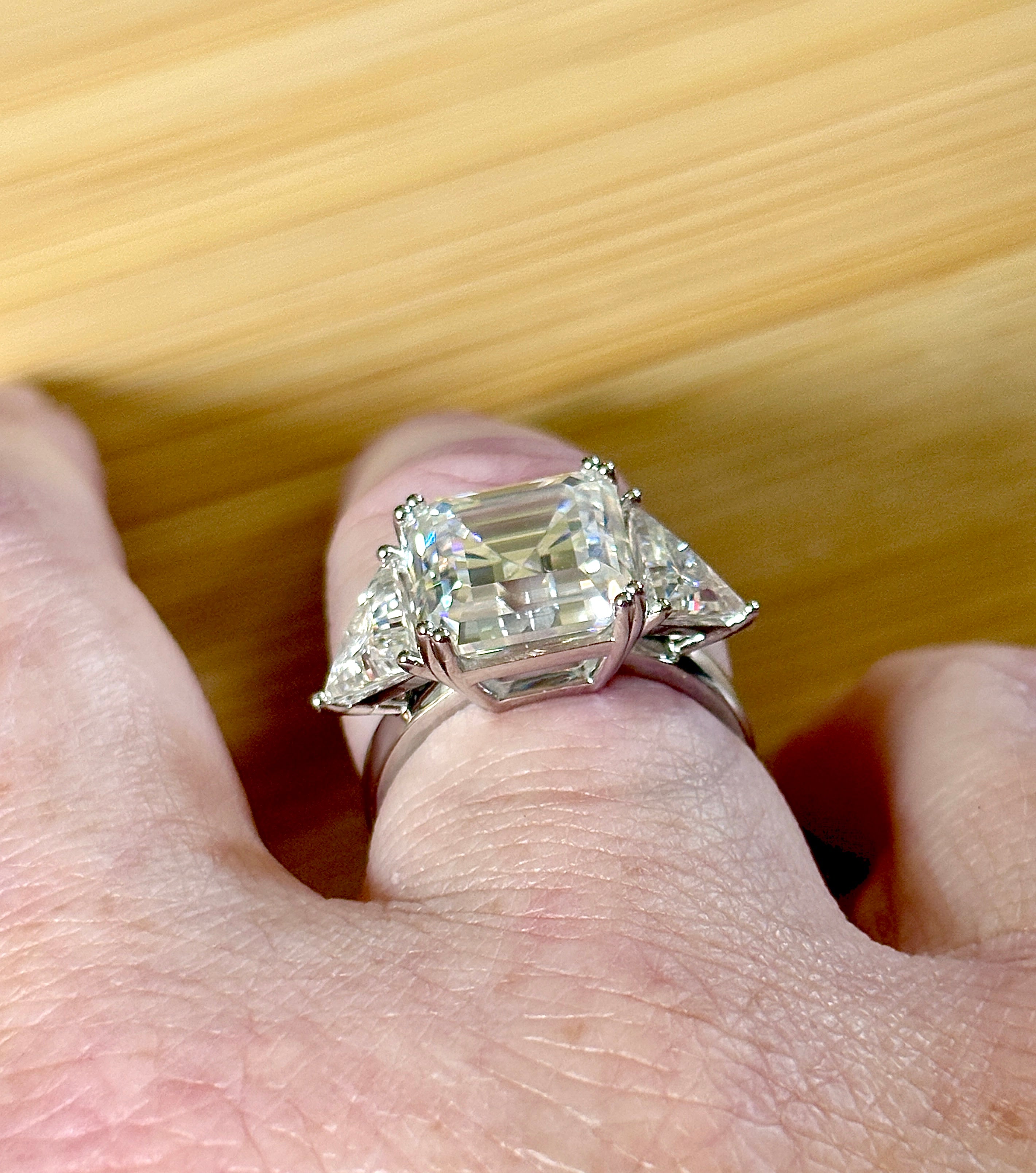 A 9.4cttw Moissanite statement ring with a 7ct Asscher-cut center stone and (2) 1.20ct Moissanite trillions, with bright 14k white rhodium!