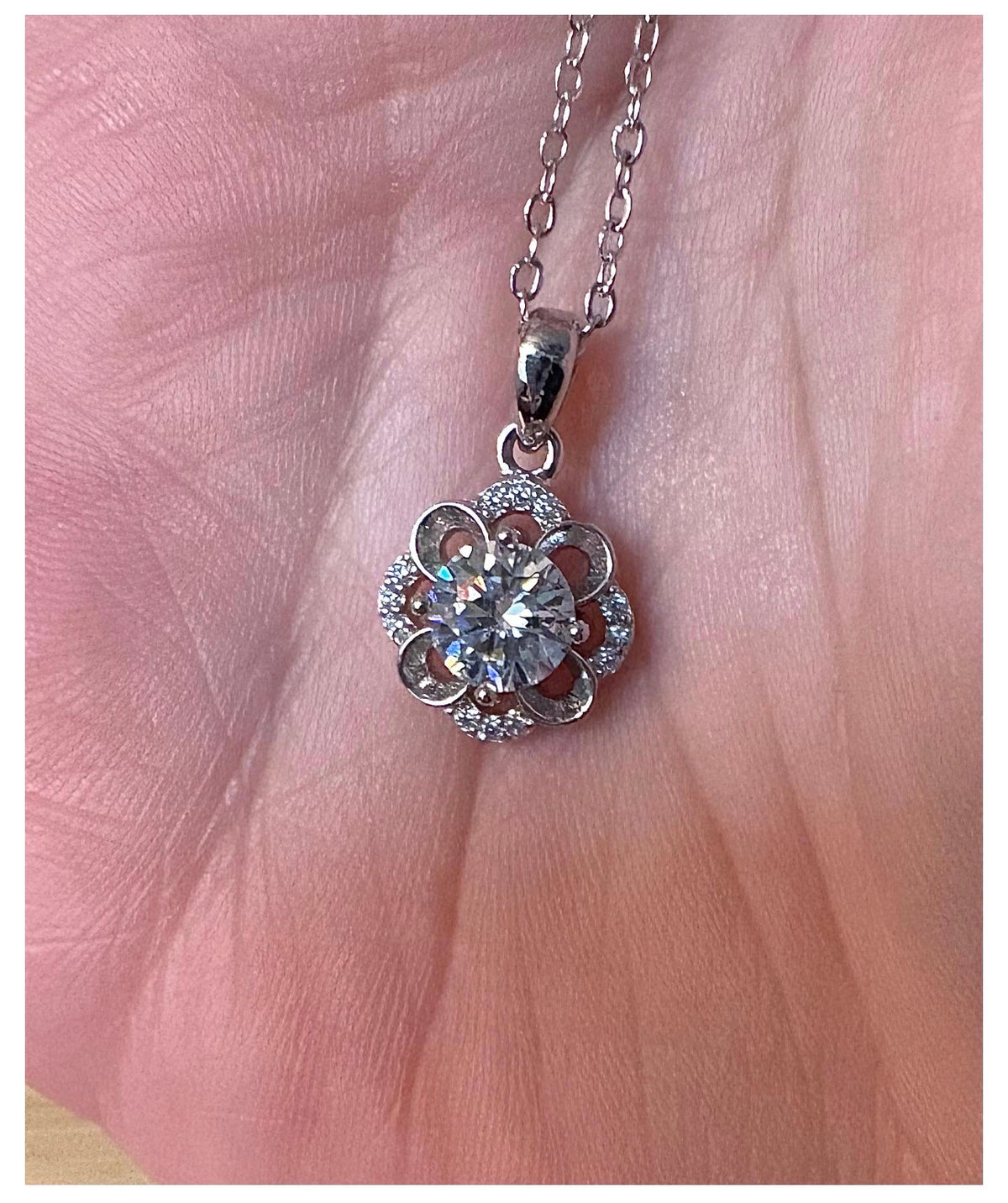 Moissanite necklace. With a floral motif, this pendant features a 1ct Moissanite nestled within alternating “petals” of silver and zircons!