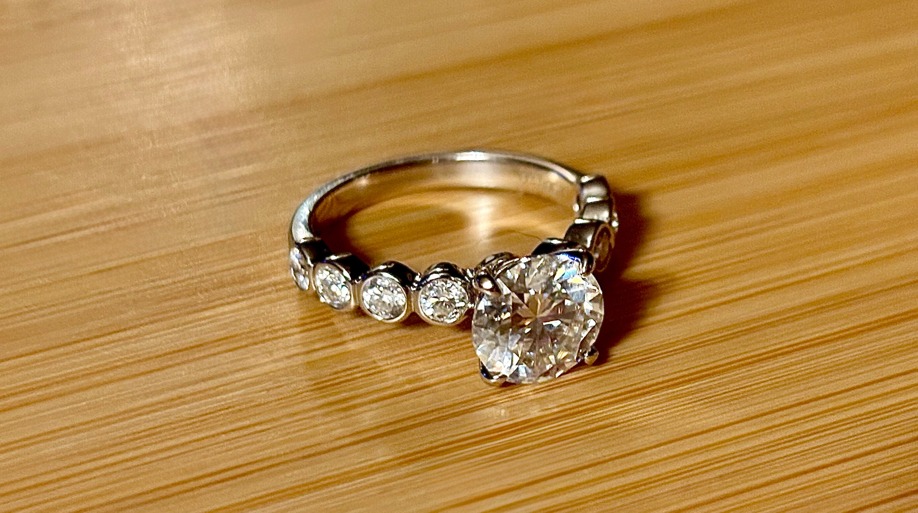 A 3.8cttw designer Moissanite ring with a certified 3ct center stone and 10-point bezel-set stones in sterling silver and 18k gold!