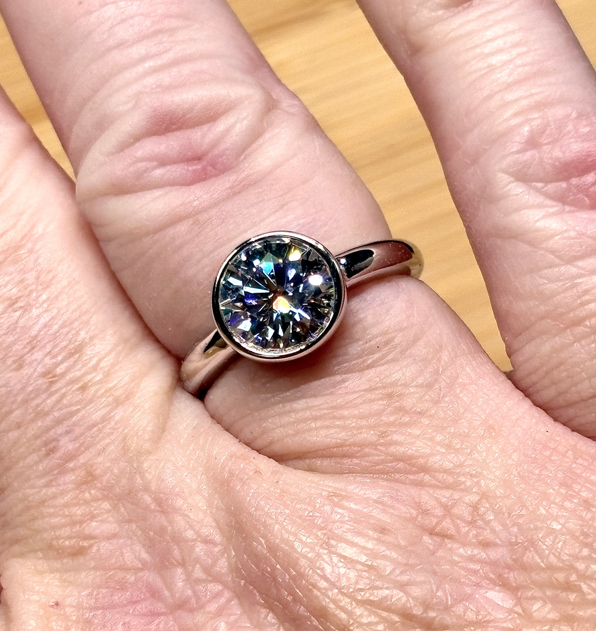 Moissanite solitaire. A 3ct certified round brilliant Moissanite in a weighty solid sterling silver bezel mounting with Seiko-electroplated 18k! A sleek, minimalist design!