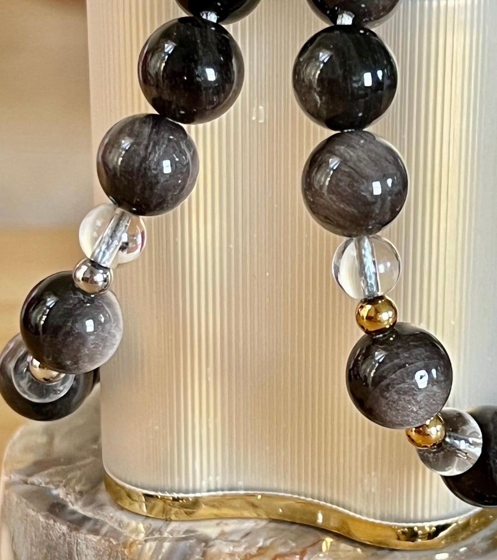 Silver sheen obsidian and clear quartz bracelet and earrings. Pair the “Silver Bells” bracelet and/or earrings with your little black party dress and be the Belle of the Ball!