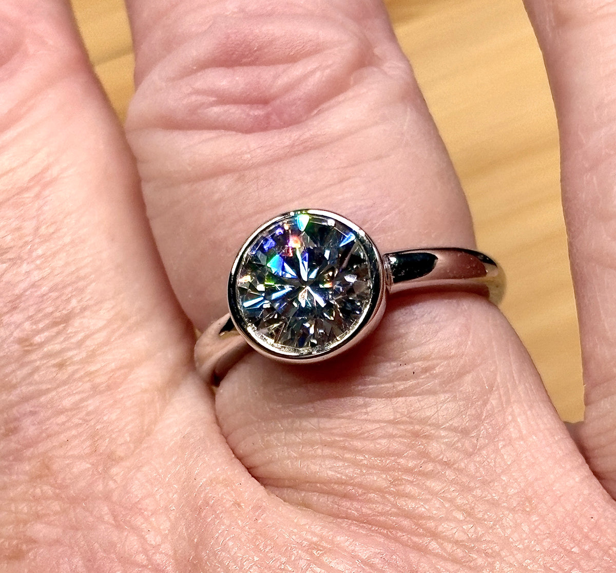 Moissanite solitaire. A 3ct certified round brilliant Moissanite in a weighty solid sterling silver bezel mounting with Seiko-electroplated 18k! A sleek, minimalist design!