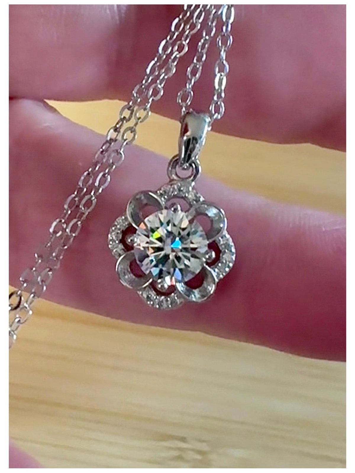 Moissanite necklace. With a floral motif, this pendant features a 1ct Moissanite nestled within alternating “petals” of silver and zircons!
