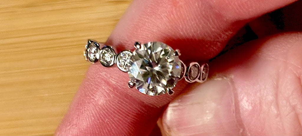 A 3.8cttw designer Moissanite ring with a certified 3ct center stone and 10-point bezel-set stones in sterling silver and 18k gold!