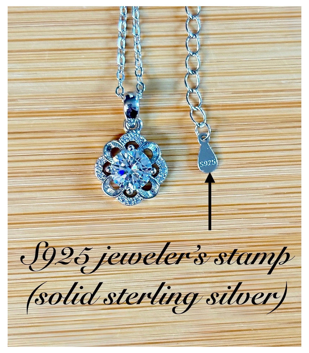 Moissanite necklace. With a floral motif, this pendant features a 1ct Moissanite nestled within alternating “petals” of silver and zircons!
