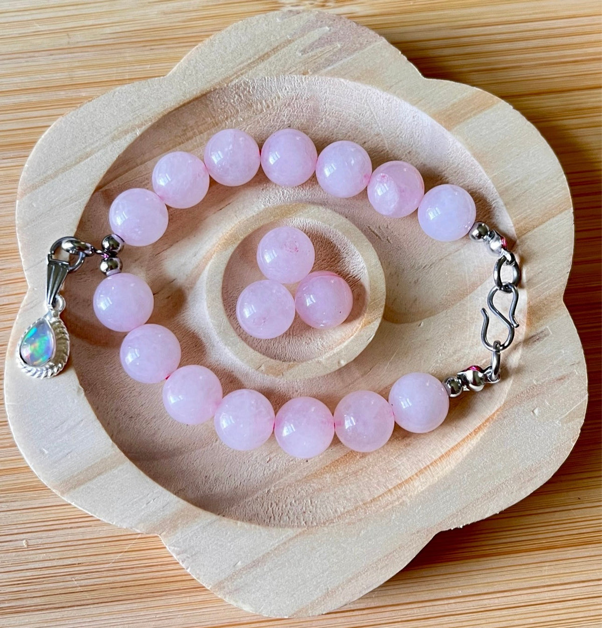 Madagascar rose quartz bracelet. 10mm beads with stainless steel components. The featured sterling silver pendants are sold separately.