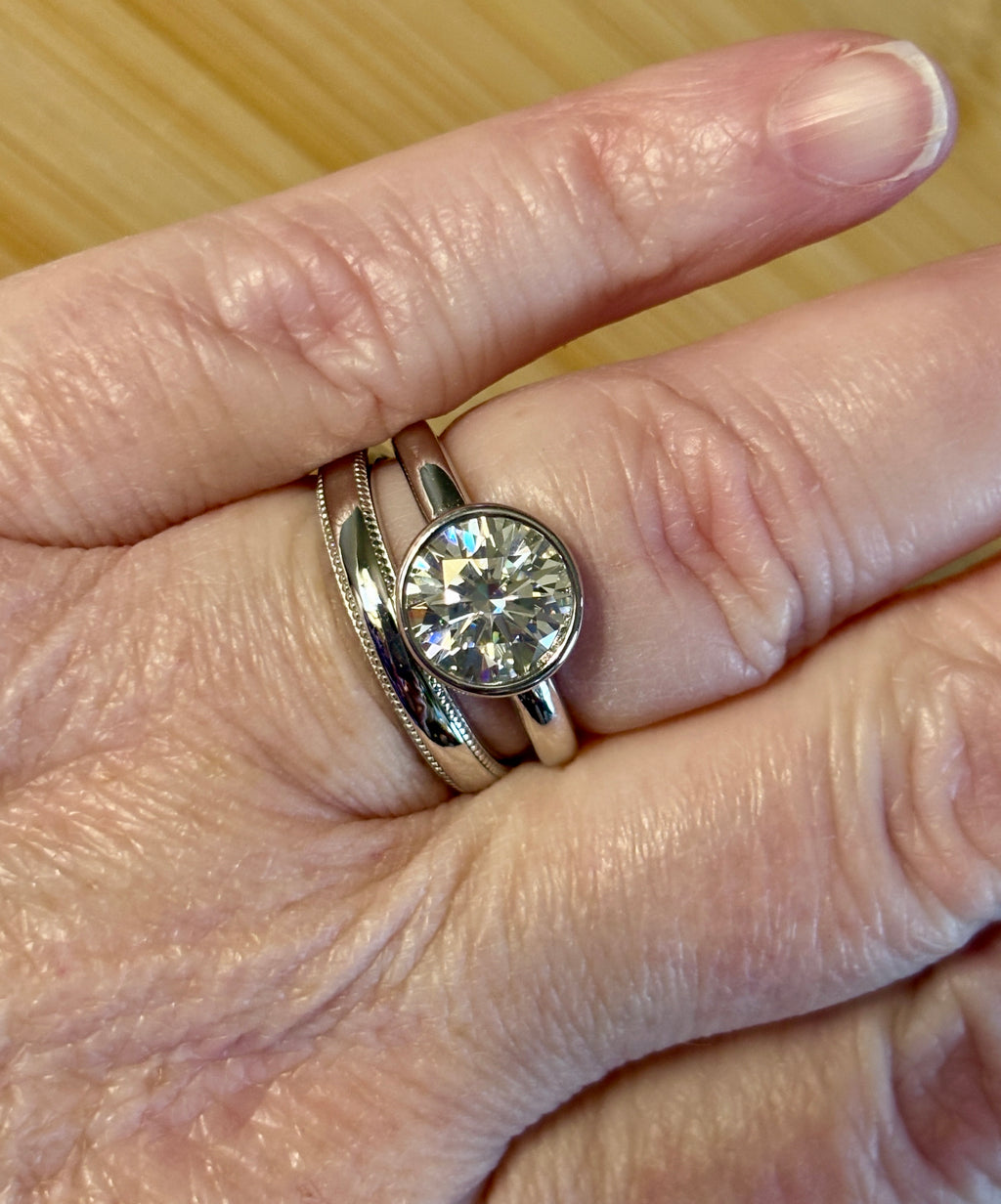 Moissanite solitaire. A 3ct certified round brilliant Moissanite in a weighty solid sterling silver bezel mounting with Seiko-electroplated 18k! A sleek, minimalist design!