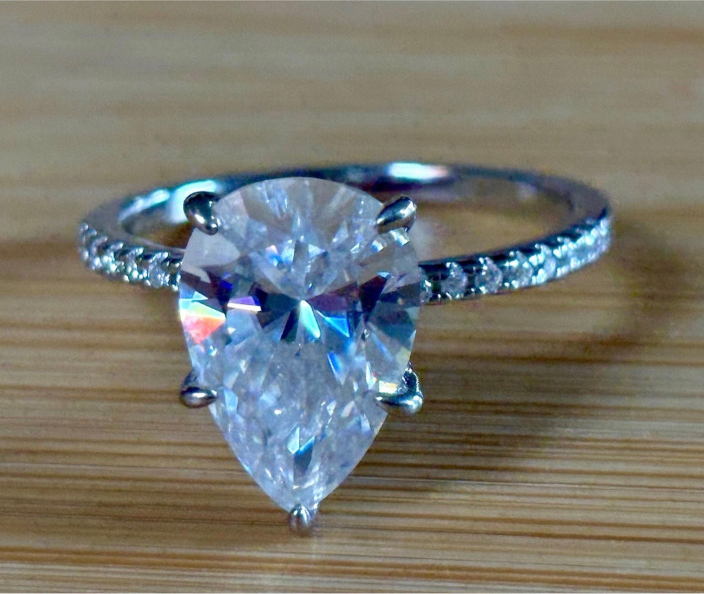 A certified 5ct pear-cut Moissanite solitaire in 925 sterling OR 935 Argentium silver with 18k, with pavé-set Moissanite shoulders and Moissanite hidden halo!