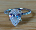 A certified 5ct pear-cut Moissanite solitaire in 925 sterling OR 935 Argentium silver with 18k, with pavé-set Moissanite shoulders and Moissanite hidden halo!