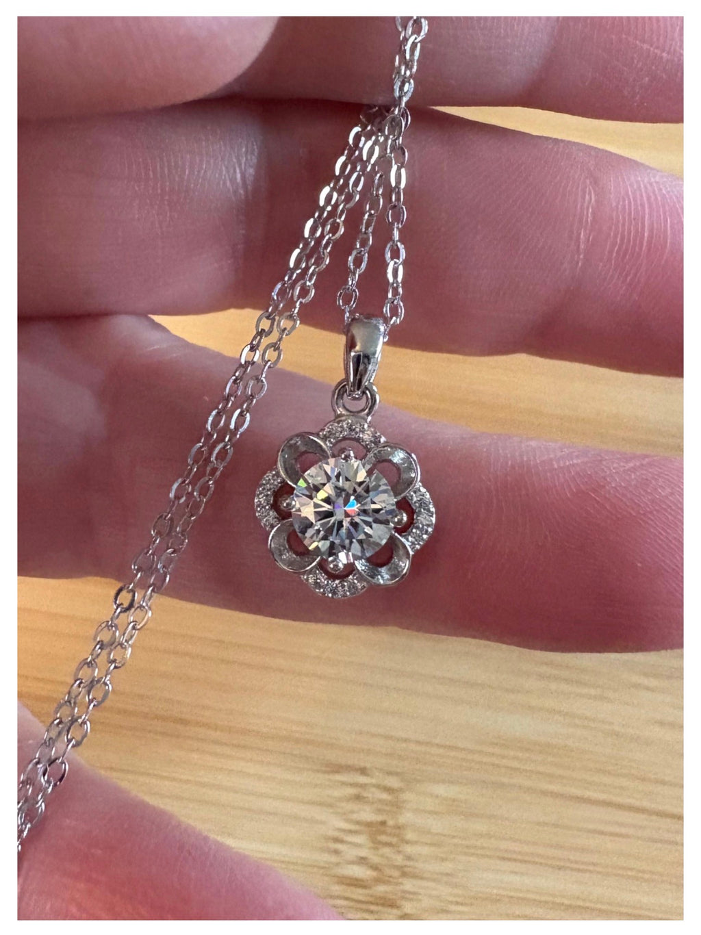Moissanite necklace. With a floral motif, this pendant features a 1ct Moissanite nestled within alternating “petals” of silver and zircons!