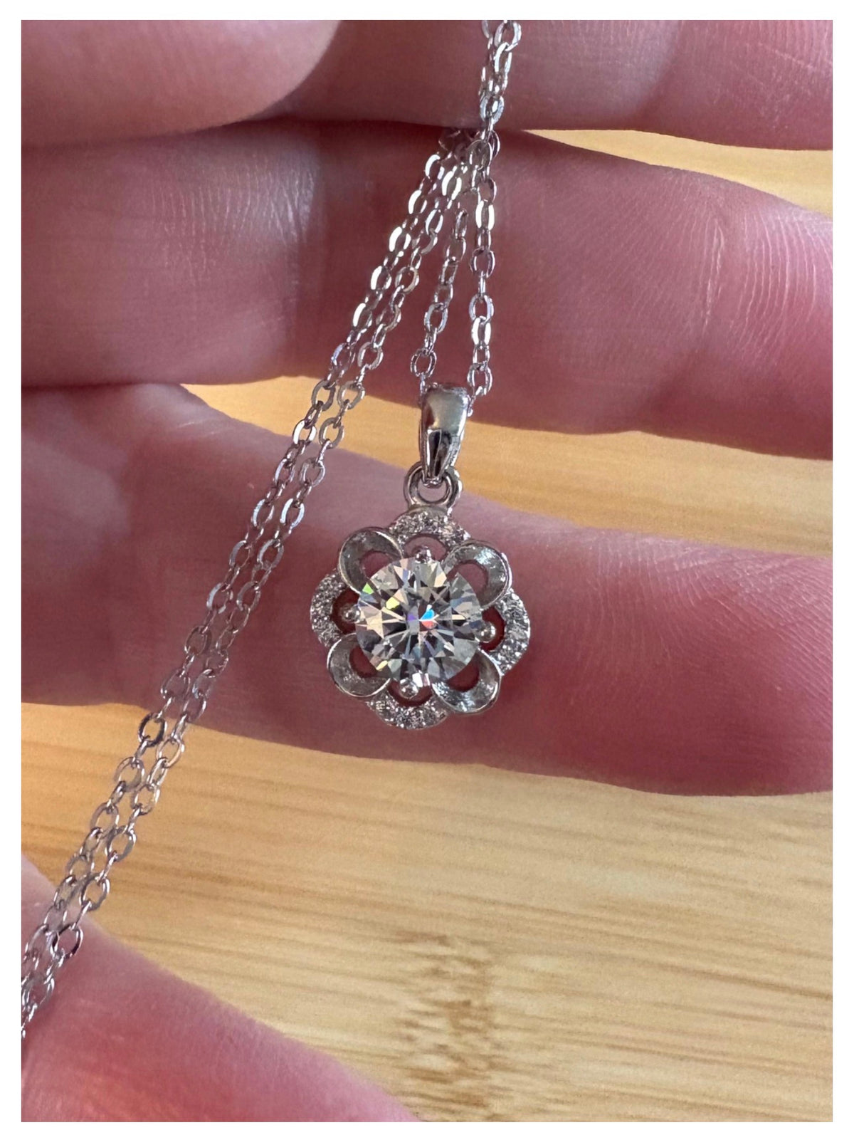 Moissanite necklace. With a floral motif, this pendant features a 1ct Moissanite nestled within alternating “petals” of silver and zircons!