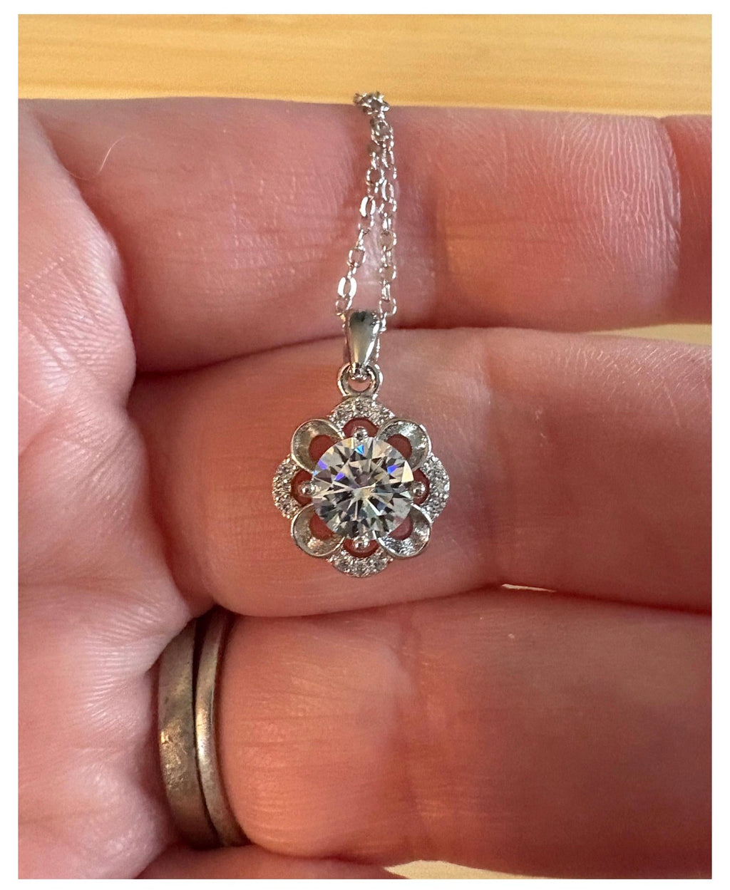 Moissanite necklace. With a floral motif, this pendant features a 1ct Moissanite nestled within alternating “petals” of silver and zircons!