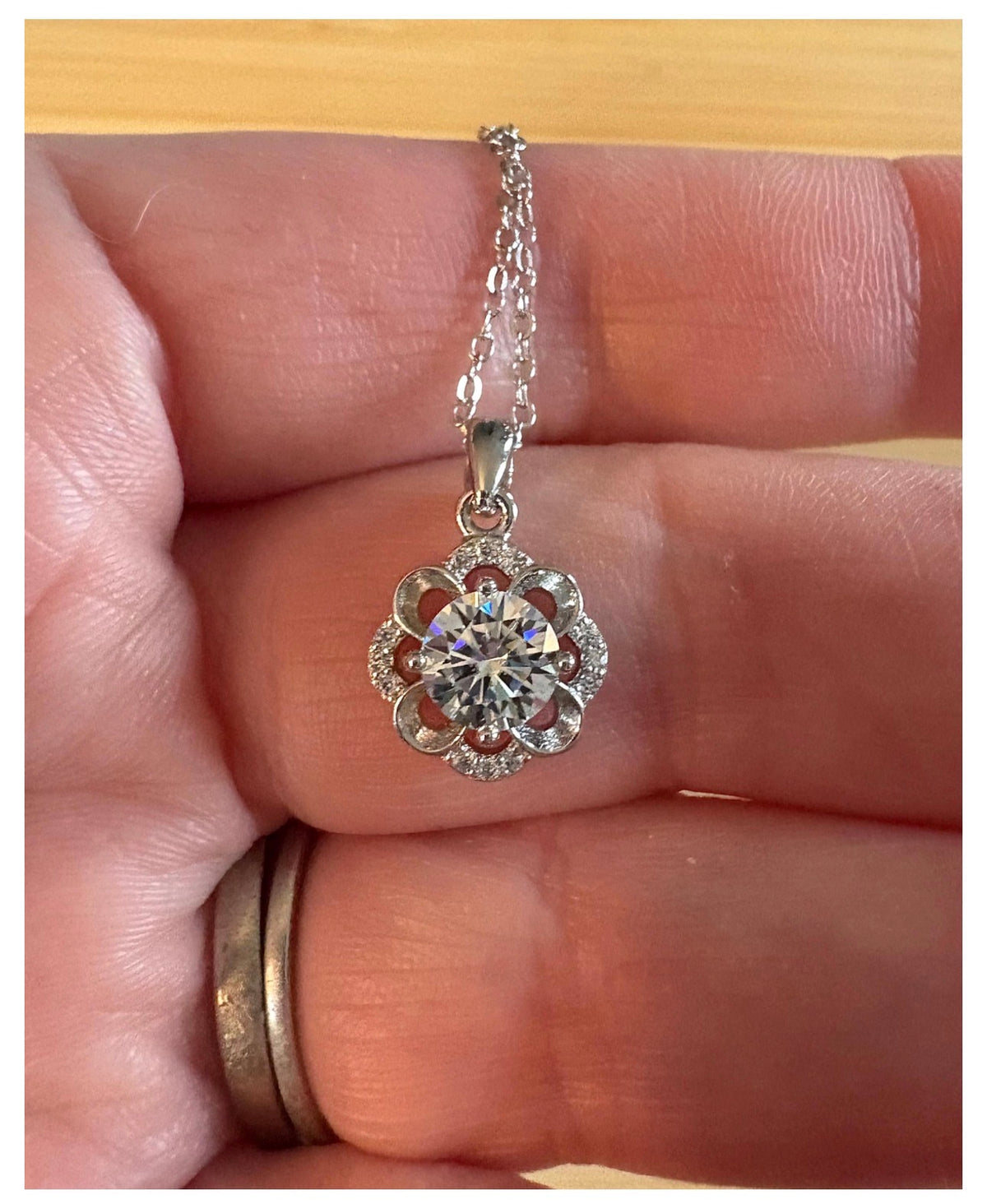 Moissanite necklace. With a floral motif, this pendant features a 1ct Moissanite nestled within alternating “petals” of silver and zircons!