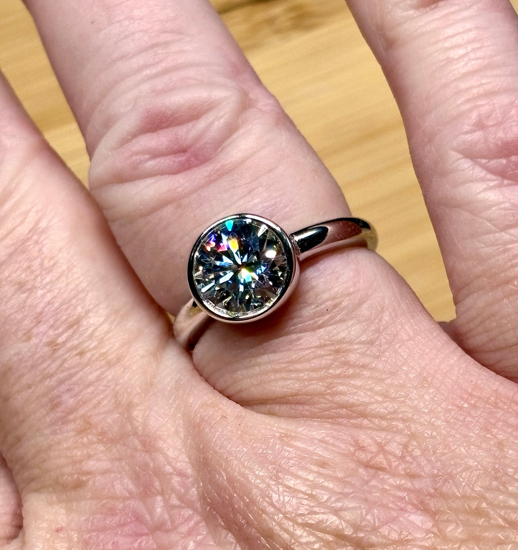Moissanite solitaire. A 3ct certified round brilliant Moissanite in a weighty solid sterling silver bezel mounting with Seiko-electroplated 18k! A sleek, minimalist design!