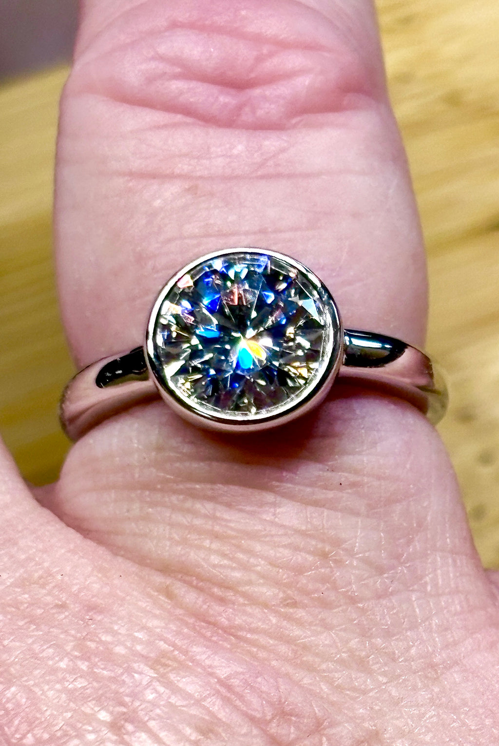 Moissanite solitaire. A 3ct certified round brilliant Moissanite in a weighty solid sterling silver bezel mounting with Seiko-electroplated 18k! A sleek, minimalist design!