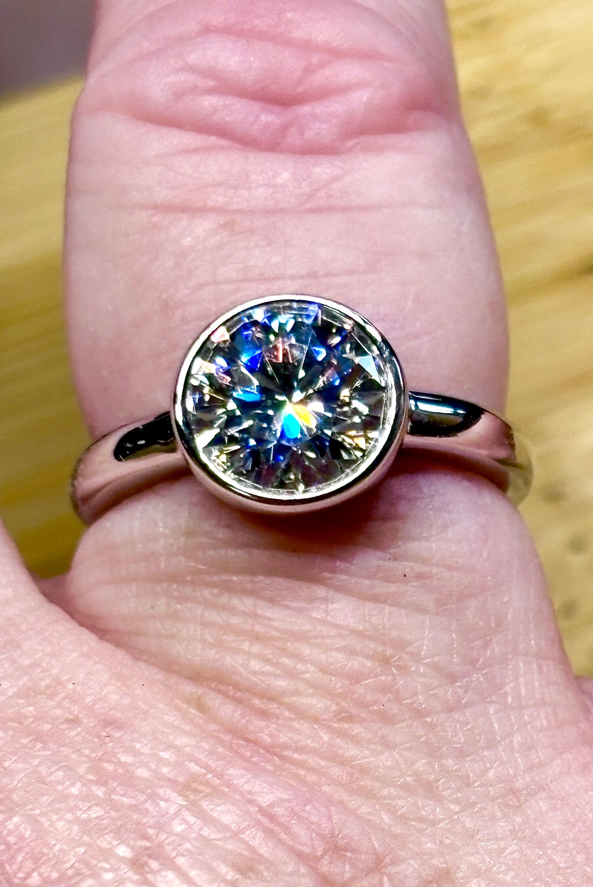 Moissanite solitaire. A 3ct certified round brilliant Moissanite in a weighty solid sterling silver bezel mounting with Seiko-electroplated 18k! A sleek, minimalist design!
