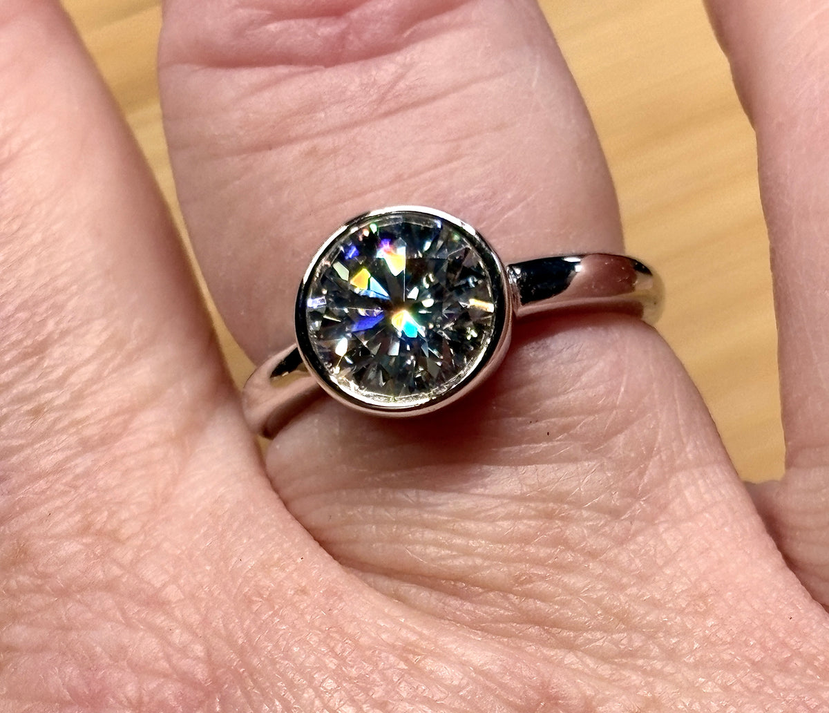 Moissanite solitaire. A 3ct certified round brilliant Moissanite in a weighty solid sterling silver bezel mounting with Seiko-electroplated 18k! A sleek, minimalist design!
