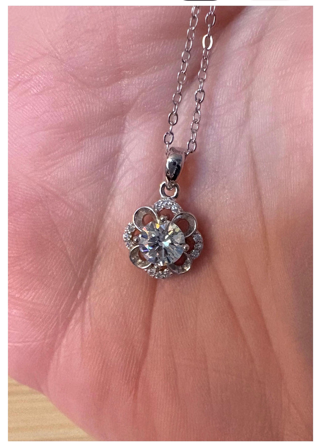 Moissanite necklace. With a floral motif, this pendant features a 1ct Moissanite nestled within alternating “petals” of silver and zircons!