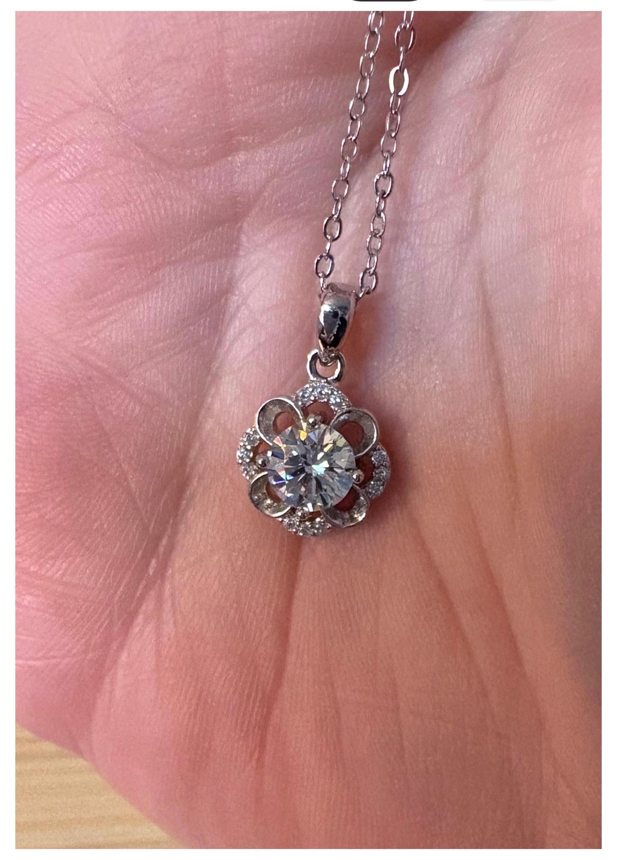Moissanite necklace. With a floral motif, this pendant features a 1ct Moissanite nestled within alternating “petals” of silver and zircons!