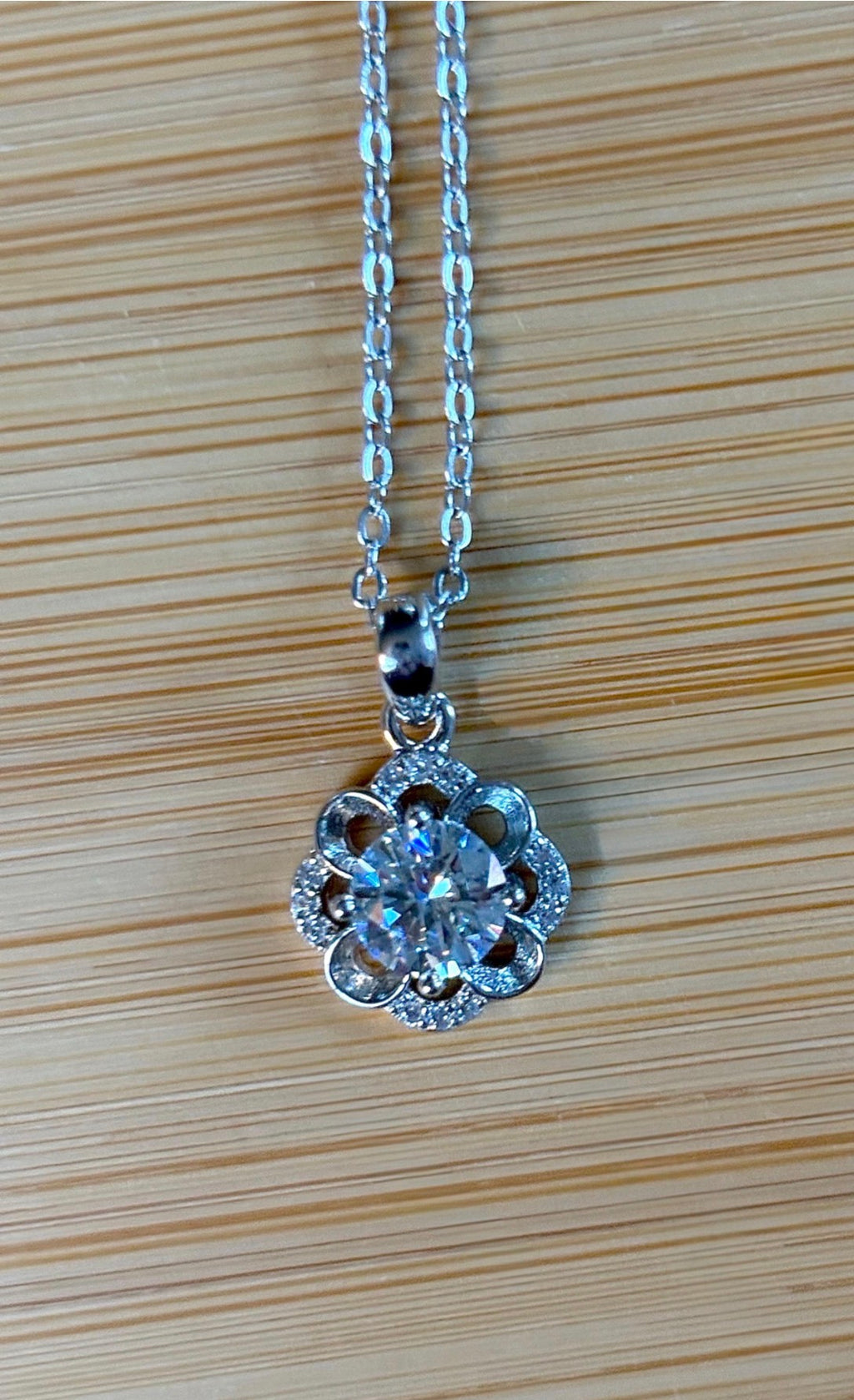Moissanite necklace. With a floral motif, this pendant features a 1ct Moissanite nestled within alternating “petals” of silver and zircons!