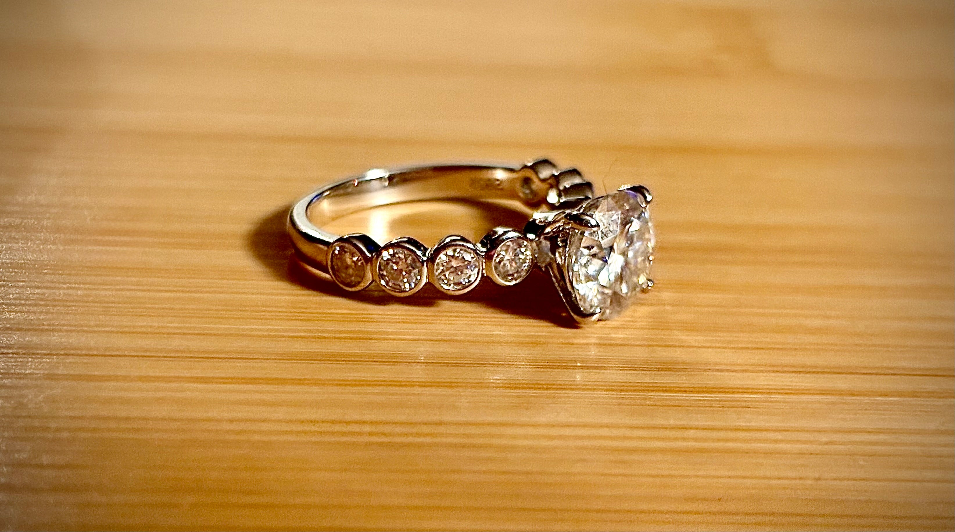 A 3.8cttw designer Moissanite ring with a certified 3ct center stone and 10-point bezel-set stones in sterling silver and 18k gold!