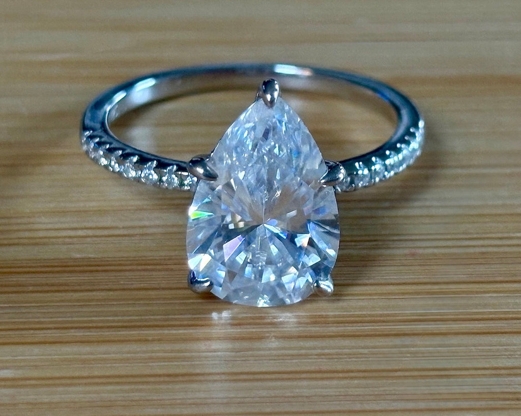 A certified 5ct pear-cut Moissanite solitaire in 925 sterling OR 935 Argentium silver with 18k, with pavé-set Moissanite shoulders and Moissanite hidden halo!