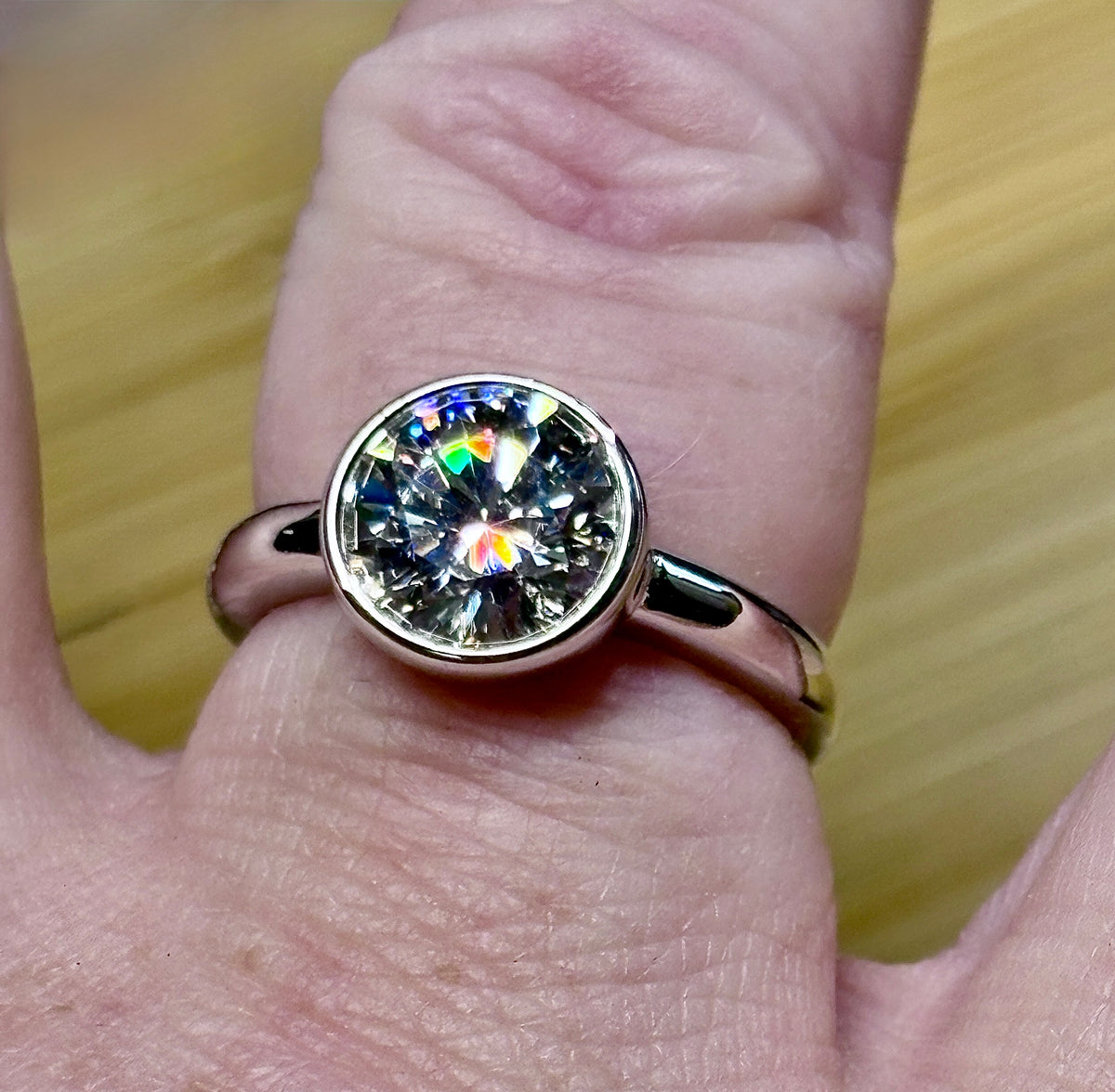 Moissanite solitaire. A 3ct certified round brilliant Moissanite in a weighty solid sterling silver bezel mounting with Seiko-electroplated 18k! A sleek, minimalist design!