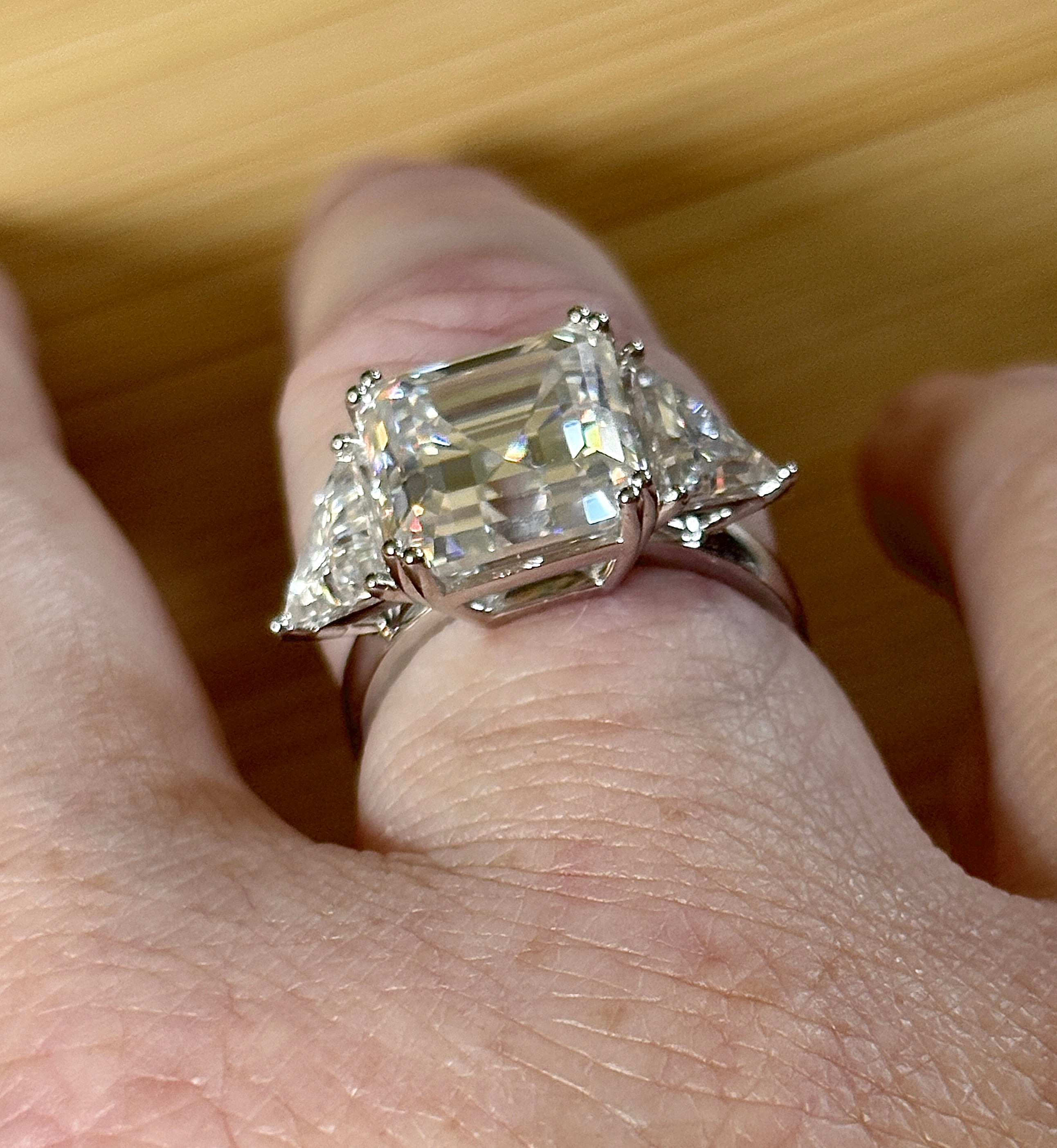 A 9.4cttw Moissanite statement ring with a 7ct Asscher-cut center stone and (2) 1.20ct Moissanite trillions, with bright 14k white rhodium!