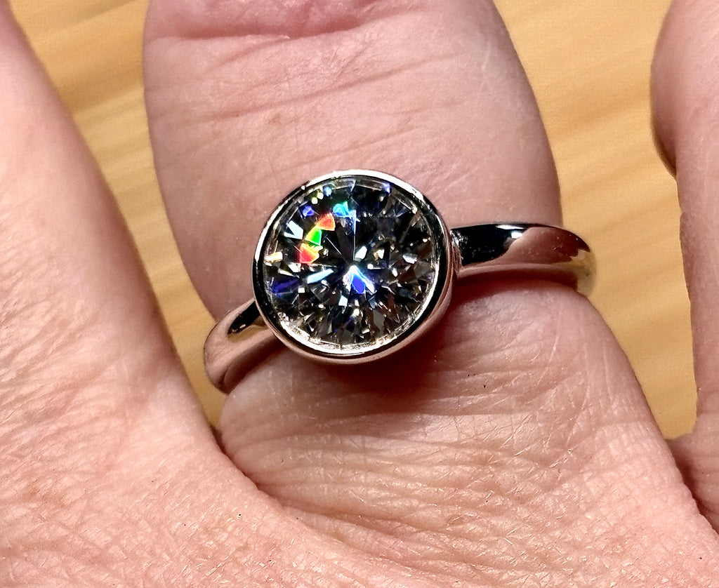 Moissanite solitaire. A 3ct certified round brilliant Moissanite in a weighty solid sterling silver bezel mounting with Seiko-electroplated 18k! A sleek, minimalist design!