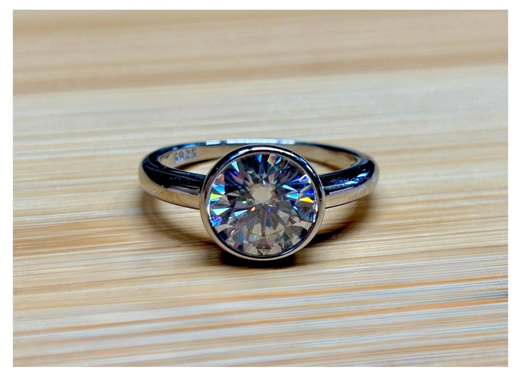 Moissanite solitaire. A 3ct certified round brilliant Moissanite in a weighty solid sterling silver bezel mounting with Seiko-electroplated 18k! A sleek, minimalist design!