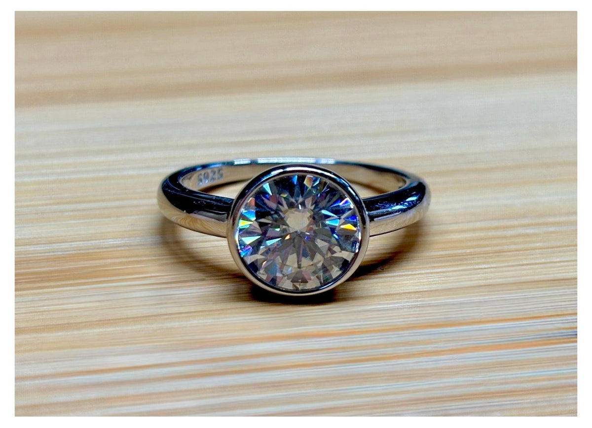 Moissanite solitaire. A 3ct certified round brilliant Moissanite in a weighty solid sterling silver bezel mounting with Seiko-electroplated 18k! A sleek, minimalist design!