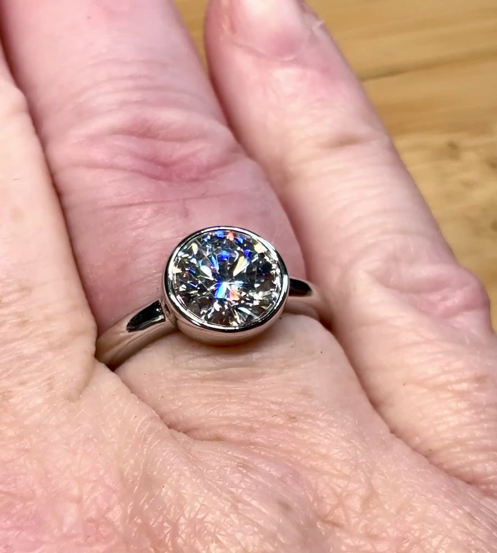 Moissanite solitaire. A 3ct certified round brilliant Moissanite in a weighty solid sterling silver bezel mounting with Seiko-electroplated 18k! A sleek, minimalist design!