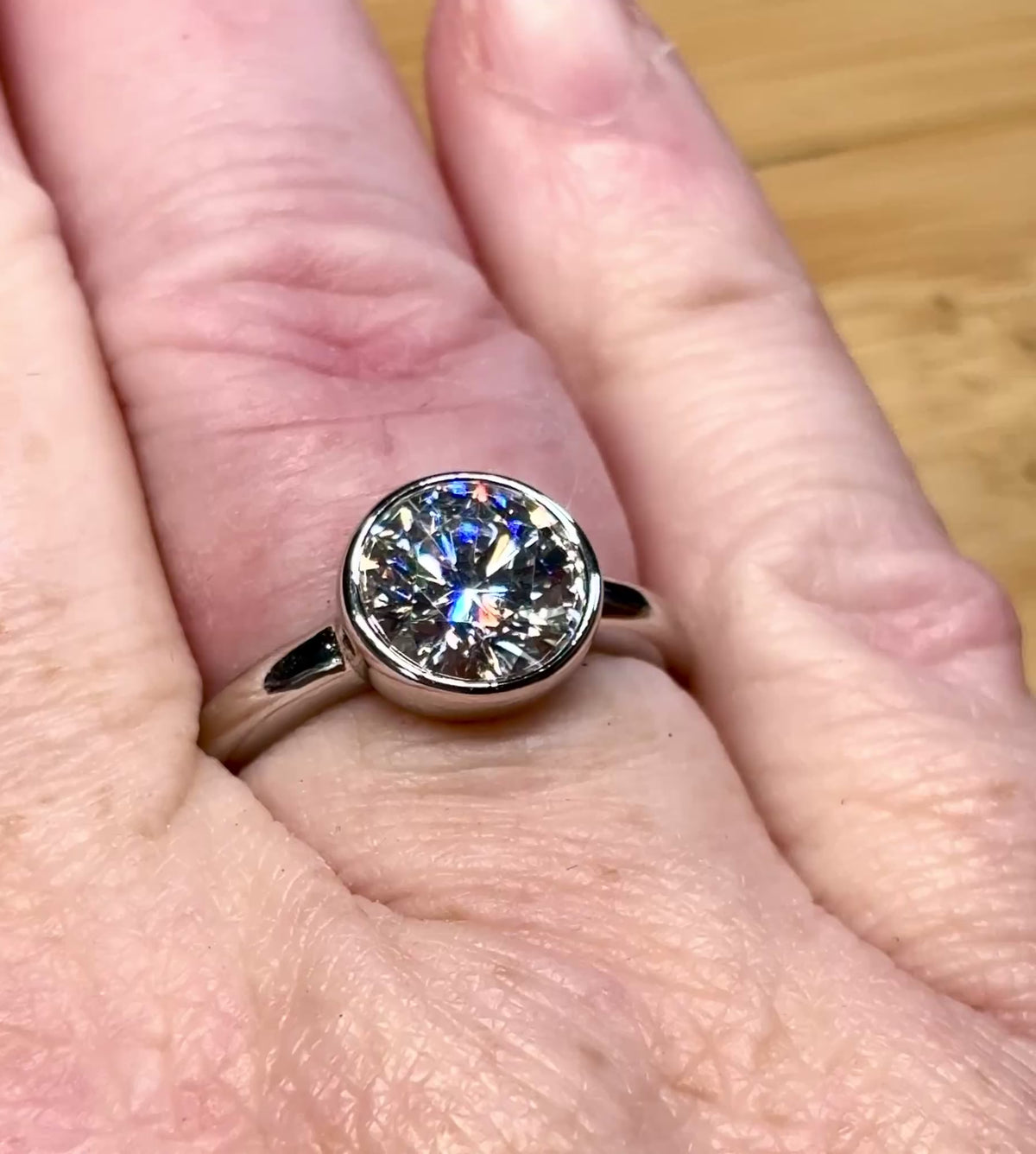 Moissanite solitaire. A 3ct certified round brilliant Moissanite in a weighty solid sterling silver bezel mounting with Seiko-electroplated 18k! A sleek, minimalist design!